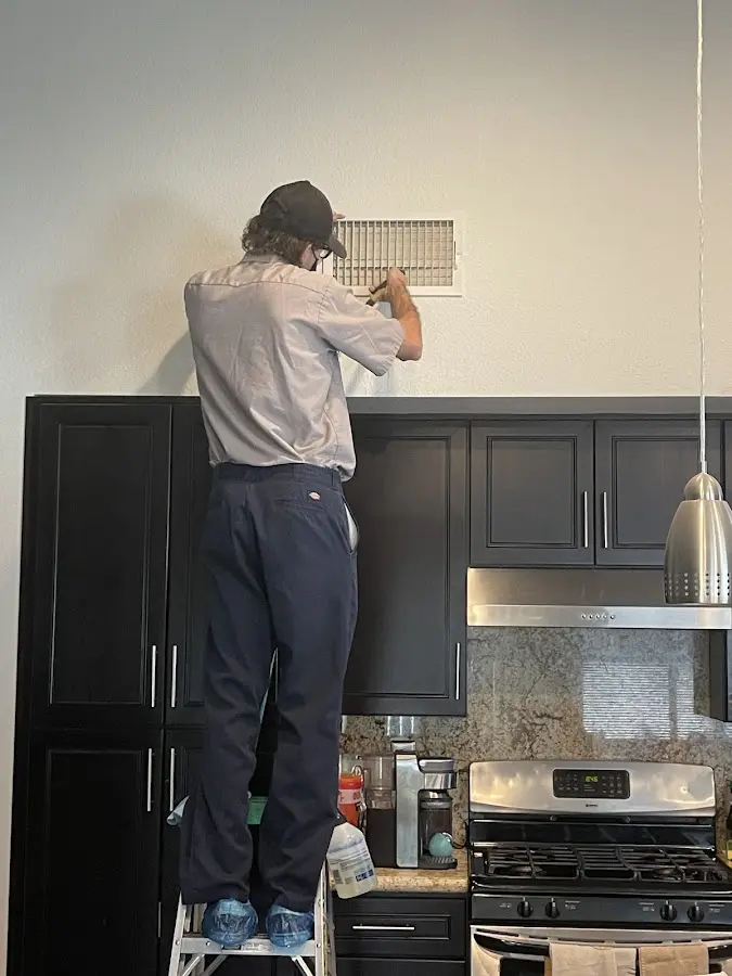 Technician inspecting an air vent during HVAC service in Goose Creek